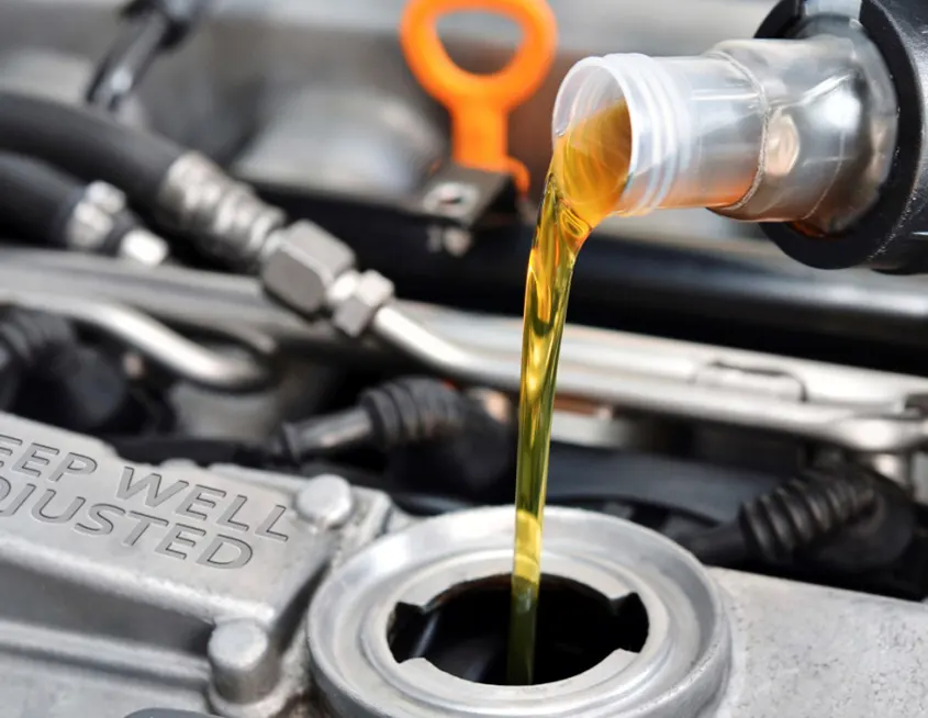 Imagen de mecánico realizando labores de mantenimento en un motor rellenando aceite
