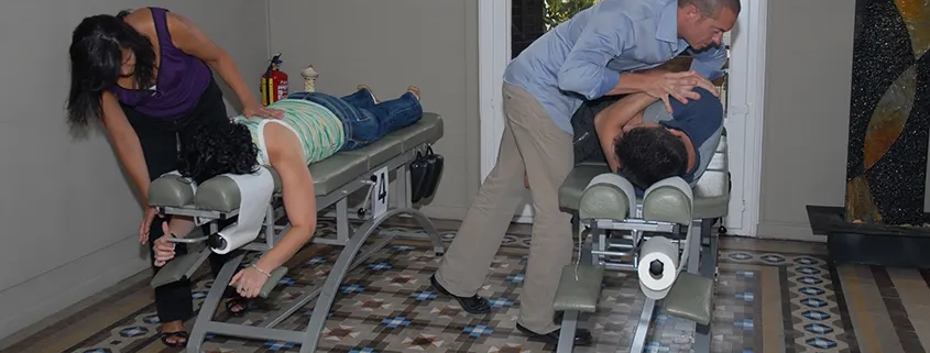 imagen de dos quiroprácticos atendiendo a dos pacientes en su consulta de Barcelona
