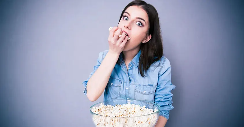 Mujer comiendo popcorn o palomitas de un gran bol